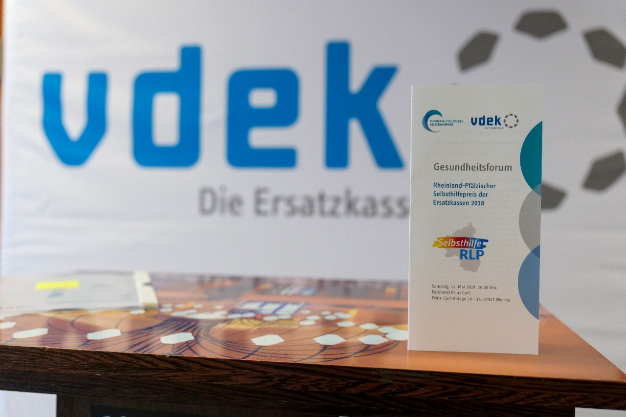 Der Flyer zum Selbsthilfepreis steht aufrecht auf dem Rednerpult. Der Flyer zum Selbsthilfepreis steht aufrecht auf dem Rednerpult.