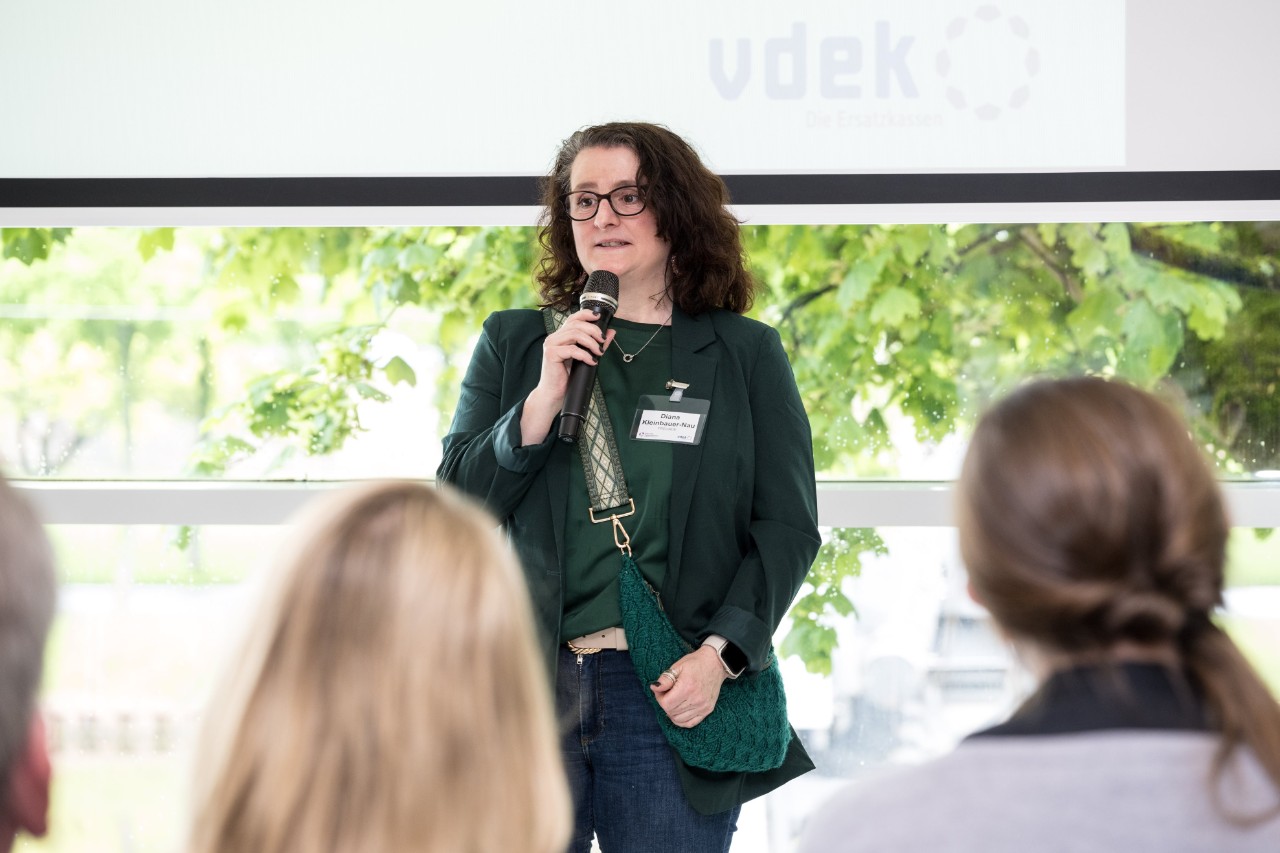 Diana Kleinbauer-Nau vom FREUNDE-Projekt weist auf ihren Stand im Foyer hin.