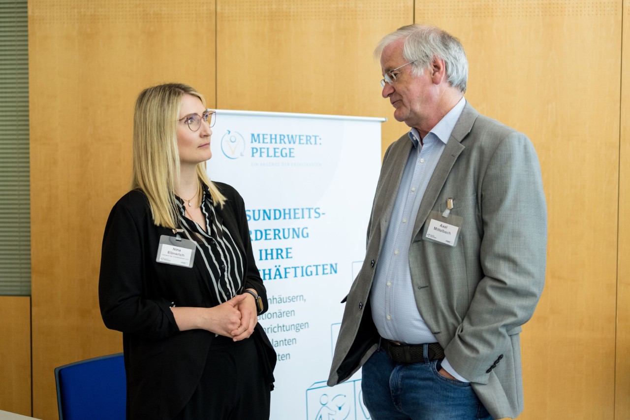 Nina Ellmerich von MEHRWERT:PFLEGE im Austausch mit einem Teilnehmer des Parlamentarischen Caf&eacute;