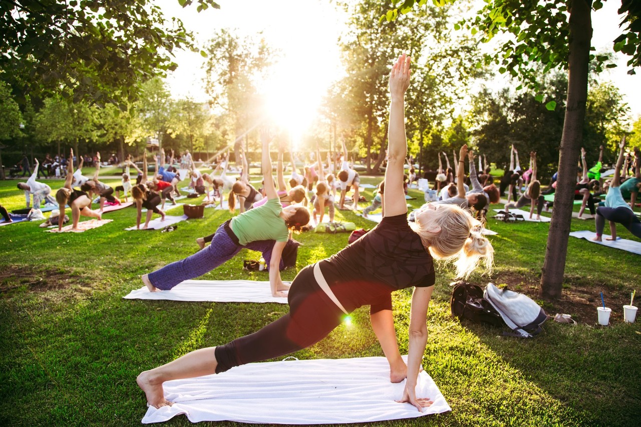 big group of adults attending a yoga class outside in park