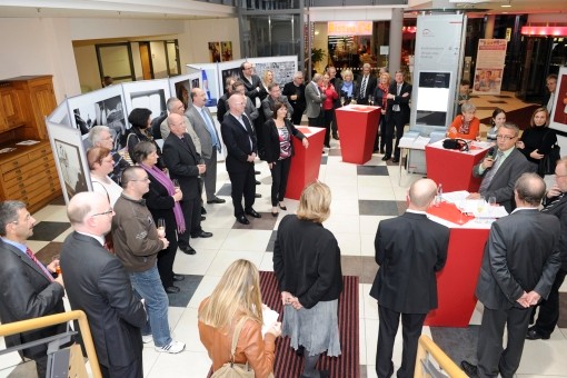 Blick auf die Ausstellungser&ouml;ffnung mit G&auml;sten, Rednern und ausgestellten Werken