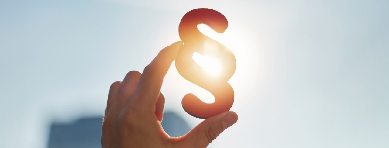hand hält haelt halten paragraphen ins licht sonne hell zeichen gesetz Justiz paragraf