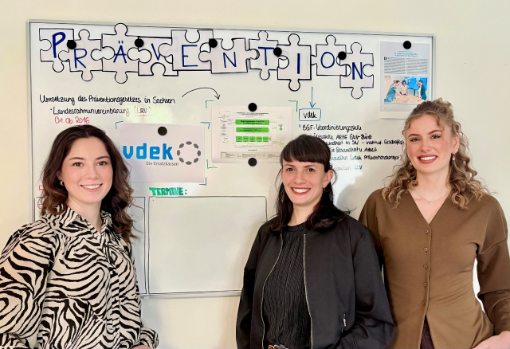 Josy Simon, Nydia-Anny Balog und Miriam Knüppel stehen vor einem Whiteboard in der vdek-Landesvertretung Sachsen
