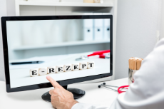 Doctor in the practice touching monitor, word e-rezept on dices, german elektronisches rezept