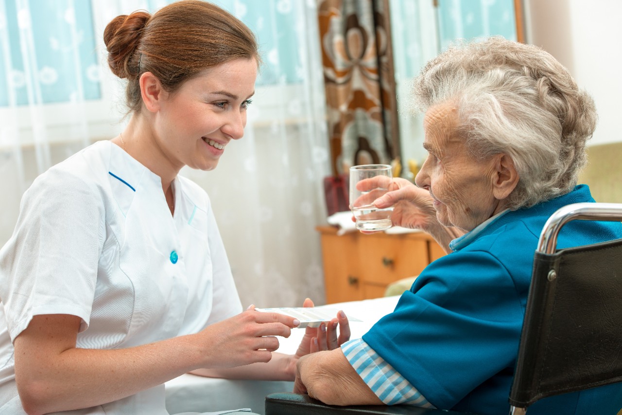 Ambulante Pflegekraft gibt Medikamente an ältere Dame