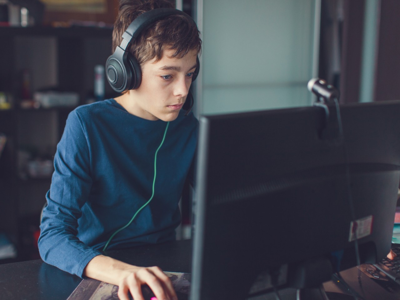 Jugendlicher spielt am Computer Kopfhörer