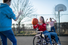 Mädchen im Rollstuhl spielt Basketball mit Freunden