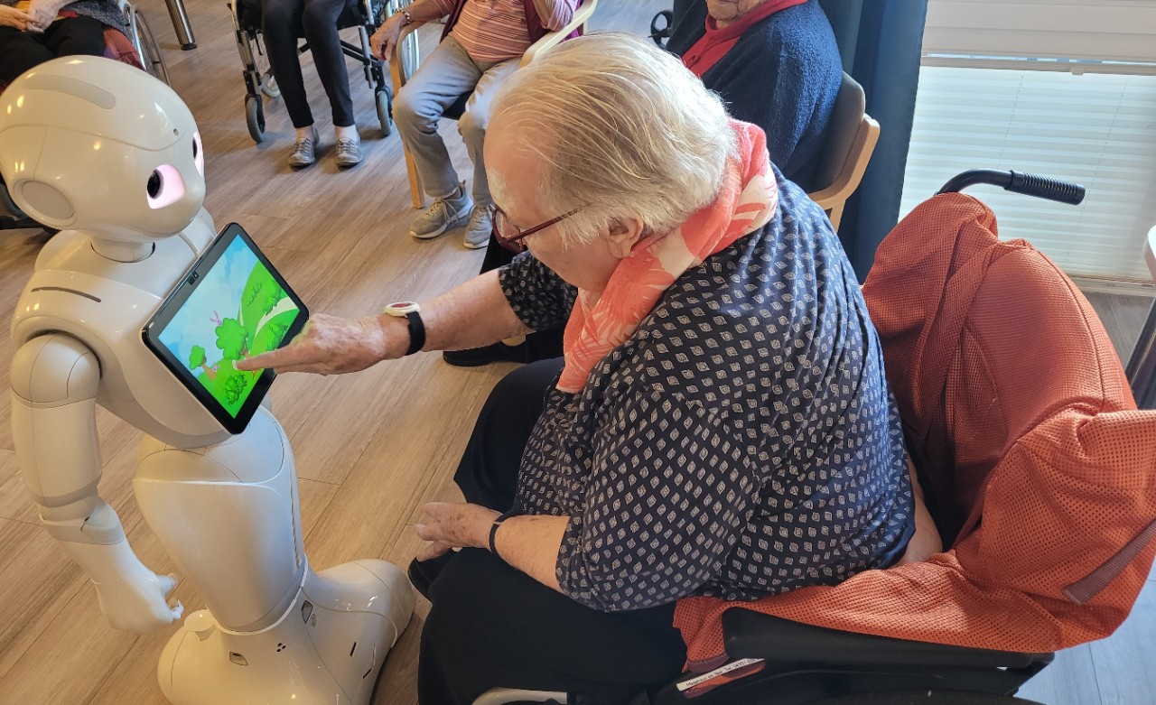 Seniorin berührt Touch-Screen am Bauch eines humanoiden Roboters
