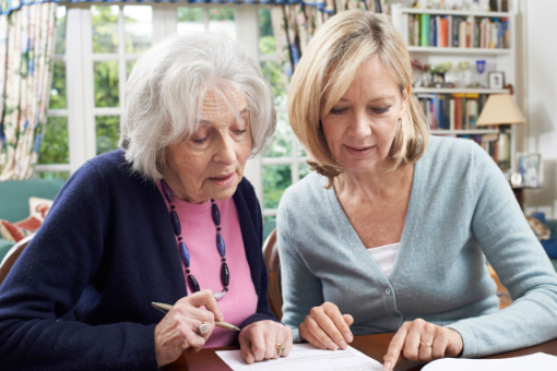 Female Neighbor Helping Senior Woman To Complete Form Female Neighbor Helping Senior Woman To Complete Form