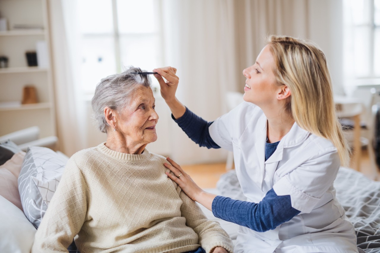 Pflegekraft kämmt Haare einer Seniorin