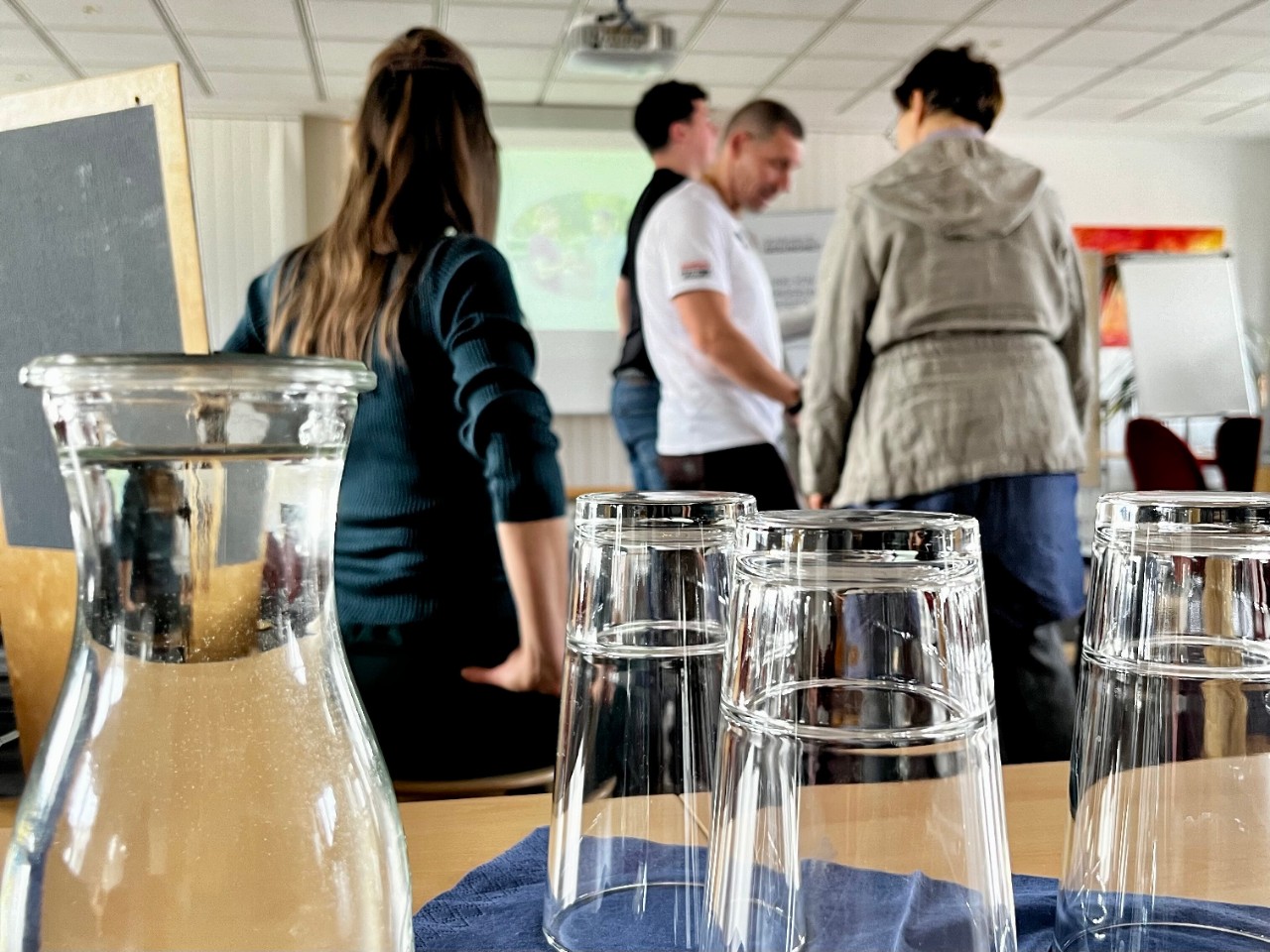Tisch mit Wassergläsern und Personen im Hintergrund
