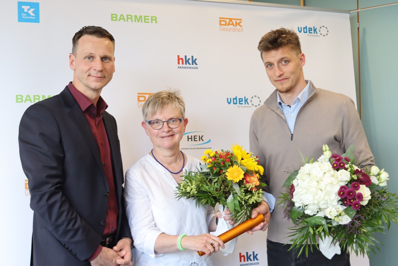 Eine Frau und zwei Männer mit Blumensträußen