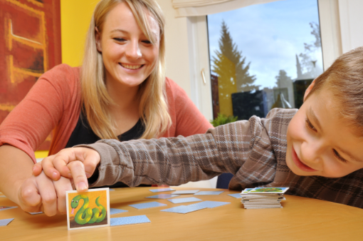 Junge Mutter spielt mit ihrem kleinen Sohn Memory auf dem Wohnzimmertisch Junge Mutter spielt mit ihrem kleinen Sohn Memory auf dem Wohnzimmertisch