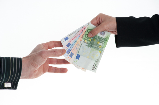 Eine Hand überreicht einer anderen Geldscheine