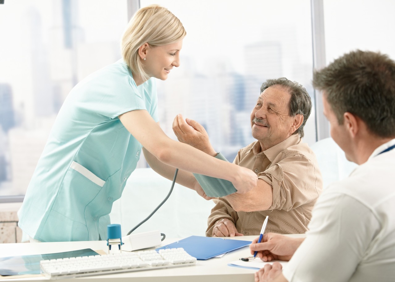 Krankenschwester misst den Blutdruck eines Patienten im Beisein eines Arztes Krankenschwester misst den Blutdruck eines Patienten im Beisein eines Arztes