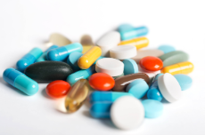 Coloured pills and capsules on white background.