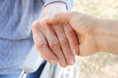 Ein Pfleger hält die Hand einer Seniorin