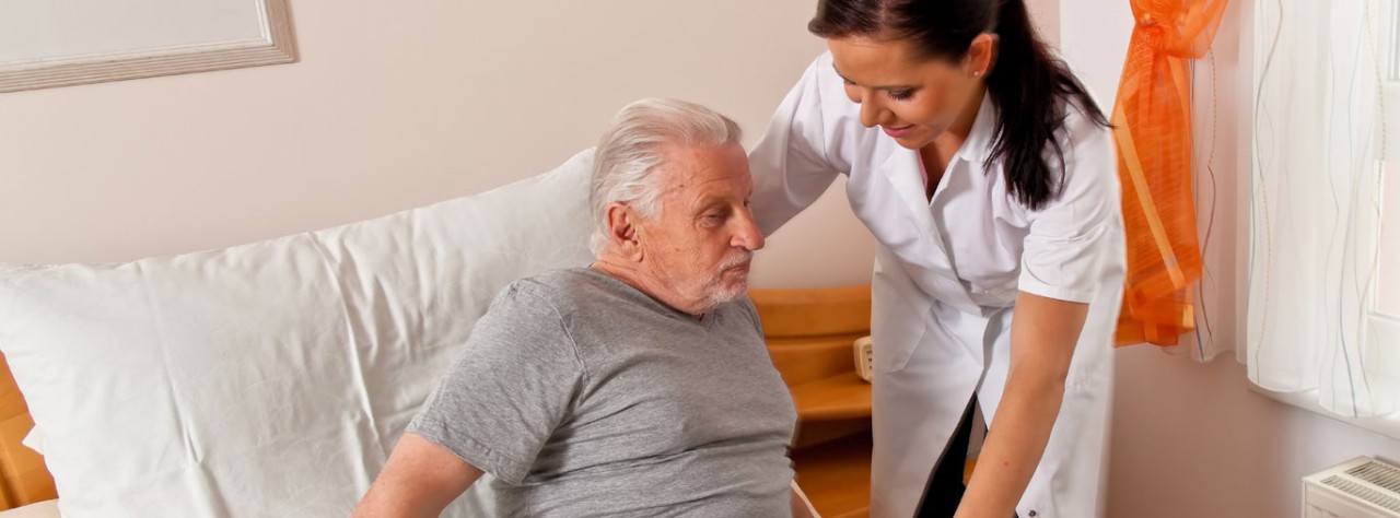 Eine Pflegerin hilft einem älteren Herren beim Aufstehen