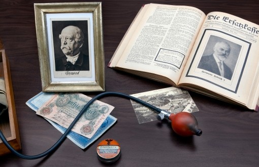 Foto zu 100 Jahre vdek: verschiedene Gegenstände wie ein Foto von Fürst Otto von Bismarck, die erste Verbandspublikation, Blutdruckmessgerät oder ein alter Fünfzig Mark Schein Foto zu 100 Jahre vdek: verschiedene Gegenstände wie ein Foto von Fürst Otto von Bismarck, die erste Verbandspublikation, Blutdruckmessgerät oder ein alter Fünfzig Mark Schein