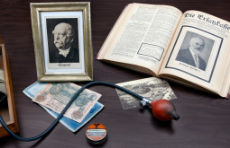 Foto zu 100 Jahre vdek: verschiedene Gegenstände wie ein Foto von Fürst Otto von Bismarck, die erste Verbandspublikation, Blutdruckmessgerät oder ein alter Fünfzig Mark Schein