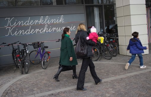 Photo vom Eingang der Charité-Kinderklinik mit zwei Frauen und Kinder abgebildet Photo vom Eingang der Charité-Kinderklinik mit zwei Frauen und Kinder abgebildet