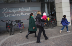 Photo vom Eingang der Charité-Kinderklinik mit zwei Frauen und Kinder abgebildet
