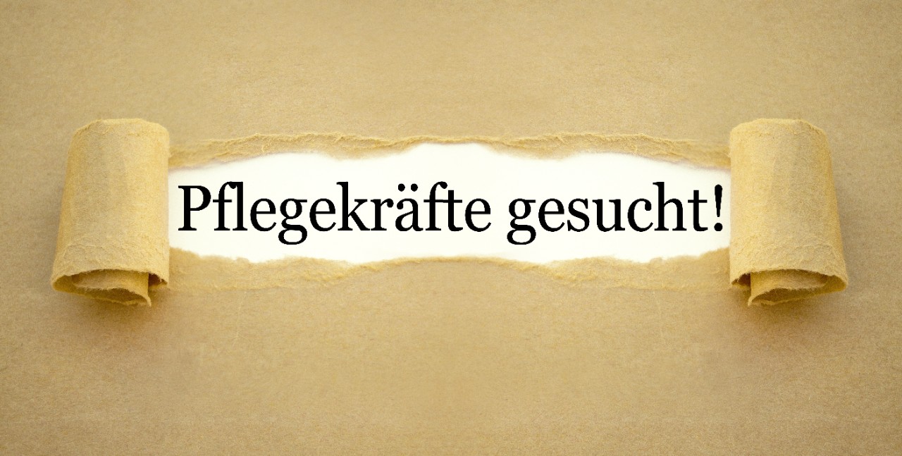 Pflegekräfte gesucht, Plakat aufgerissen inmitten der Schriftzug Pflegekräfte gesucht, Plakat aufgerissen inmitten der Schriftzug