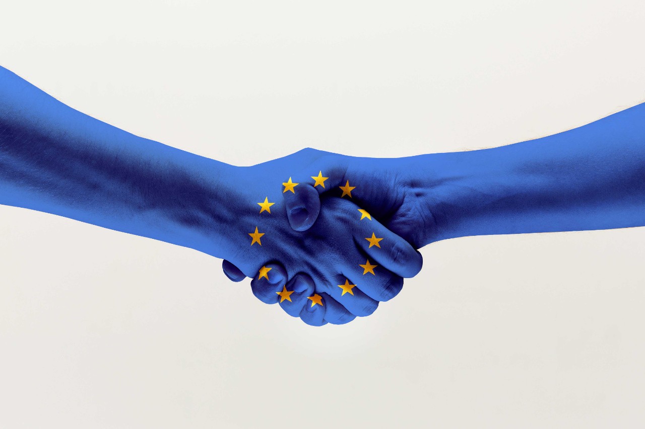 Zwei ineinandergreifende Hände in den Farben der Europäischen Union