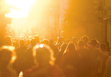 Menschenmenge in Fußgängerzone, von tief stehender Sonne beleuchtet.