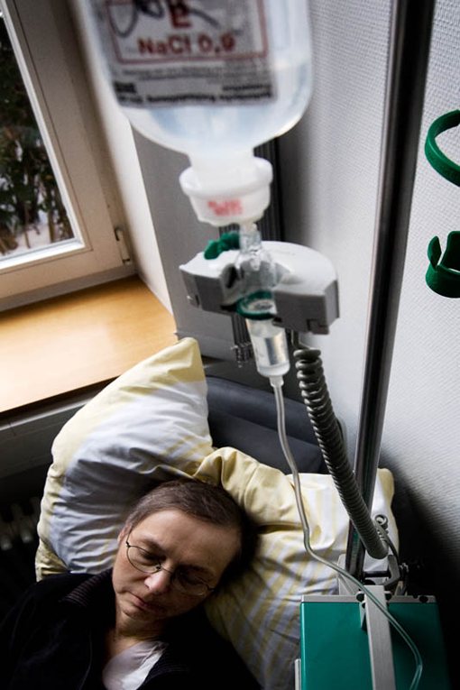 Blick von oben auf eine Frau auf dem Bett mit einer Infusion.