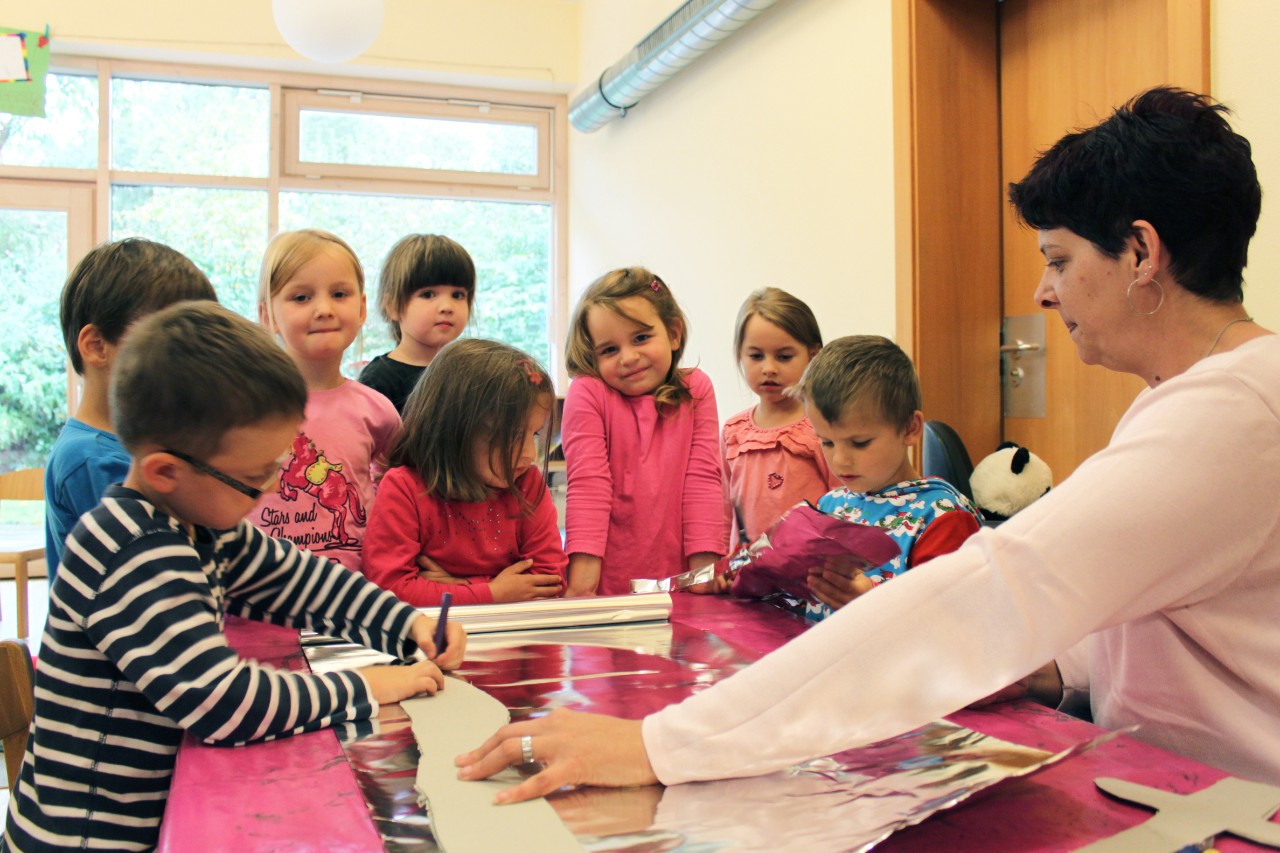 Erzieherin bastelt mit einer Gruppe von Kindern an einem Tisch