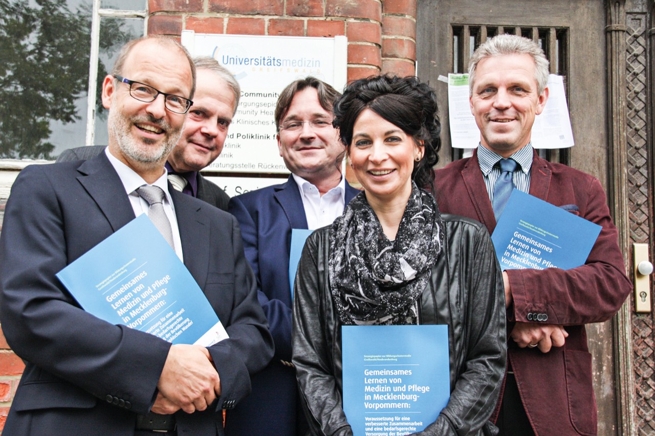 Gruppe von Menschen mit Brosch&uuml;re in den H&auml;nden vor einem Gesch&auml;ftshaus