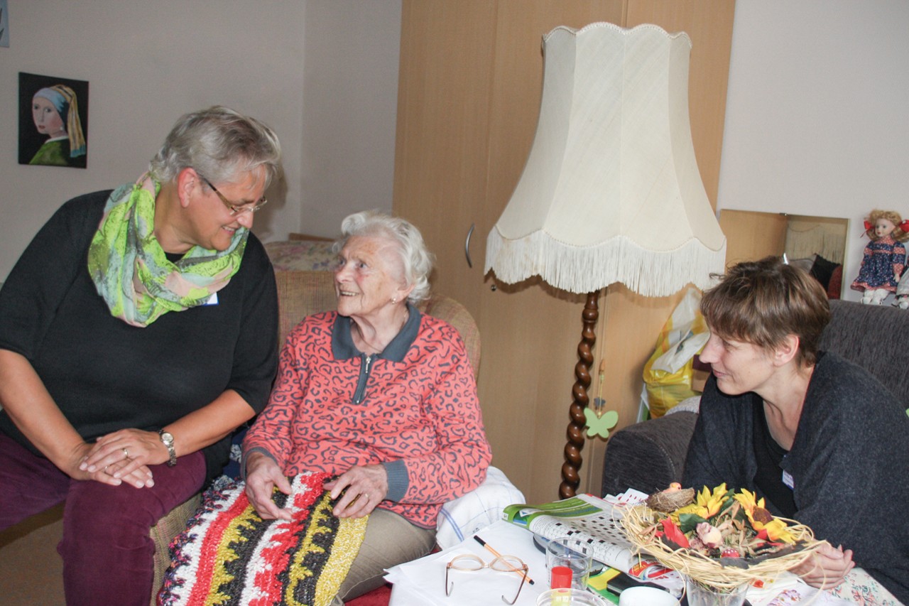Alte Frau mit zwei j&uuml;ngeren Frauen im Wohnzimmer.