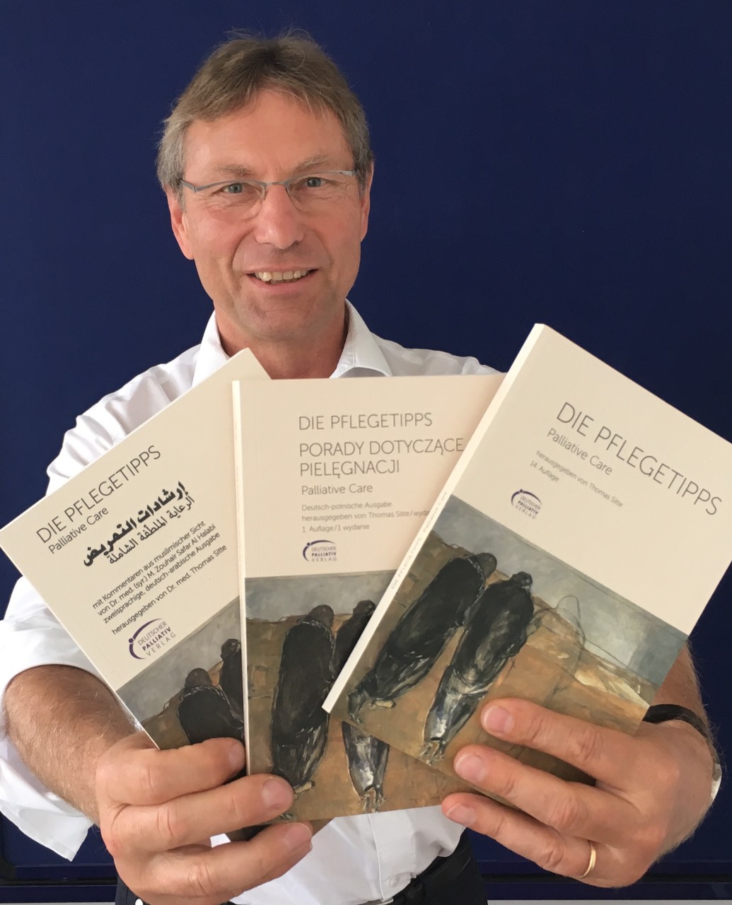 Dr. Thomas Sitte, Vorstandsvorsitzender Deutsche Palliativstiftung, hält Broschüren mit Pflegetipps in die Kamera