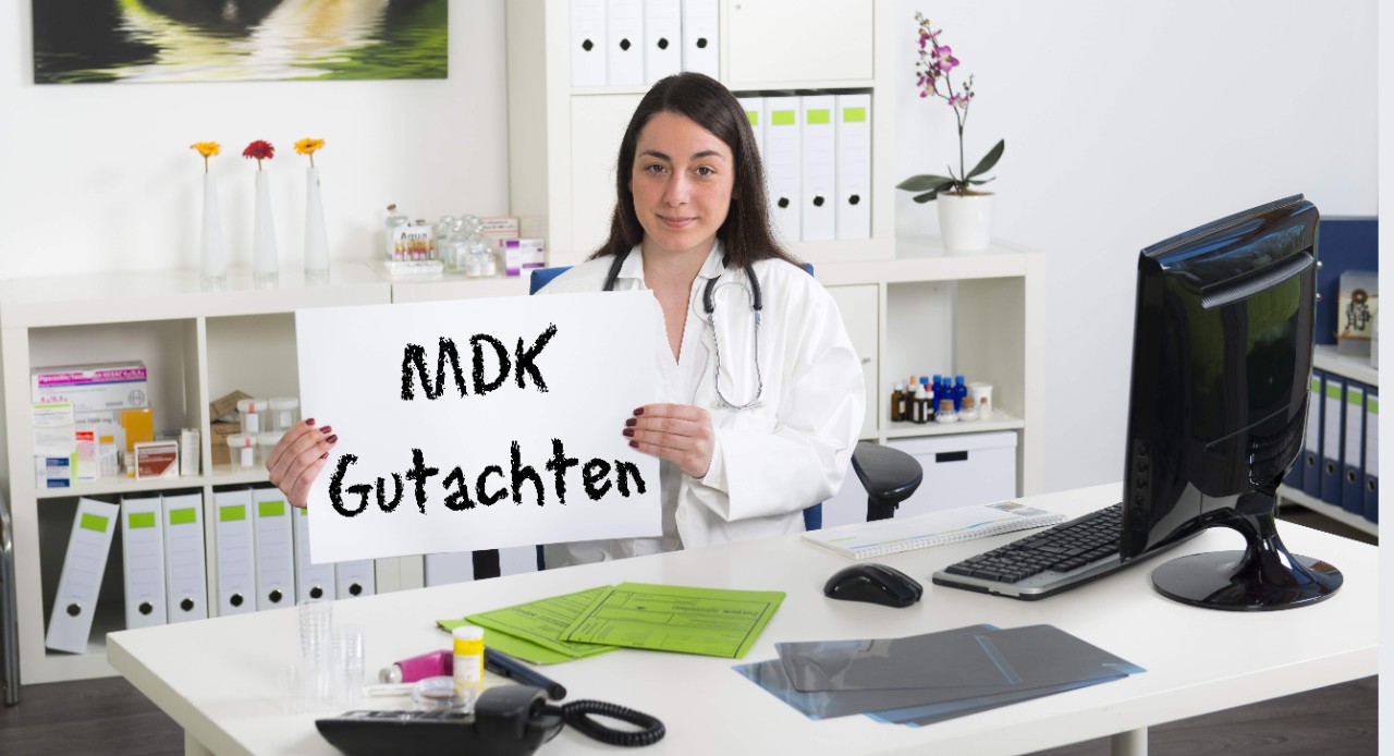 Ärztin am Schreibtisch mit Schild "MDK Gutachten"