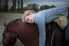 Mädchen liegt auf einem Pferd