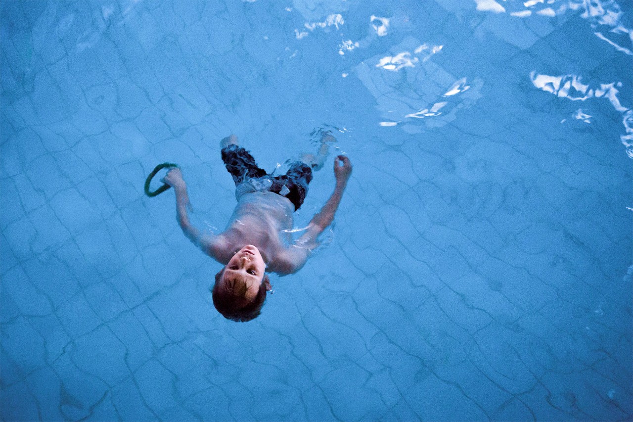 Ein Junge lässt sich in einem Schwimmbad im Wasser auf dem Rücken treiben
