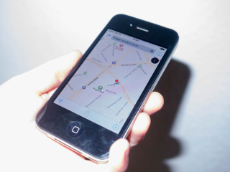 Eine Hand hält ein Handy, auf dessen Display eine Straßenkarte zu sehen ist 