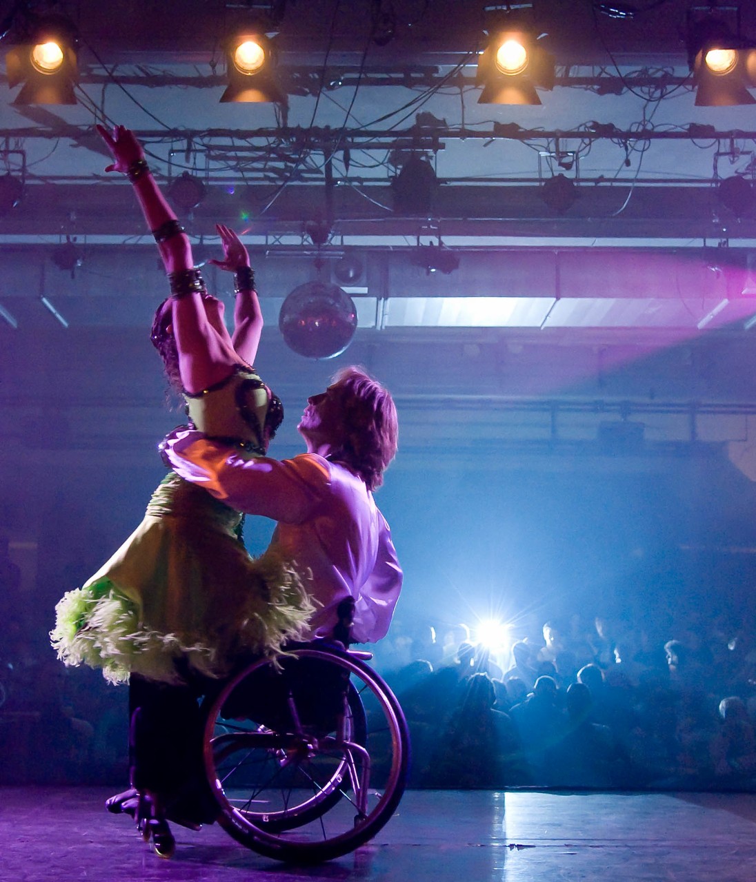 Ein Mann im Rollstuhl hebt seine Tanzpartnerin in die Höhe