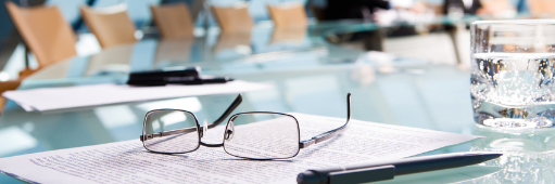 Stift, Brille und Papiere auf einem Sitzungstisch