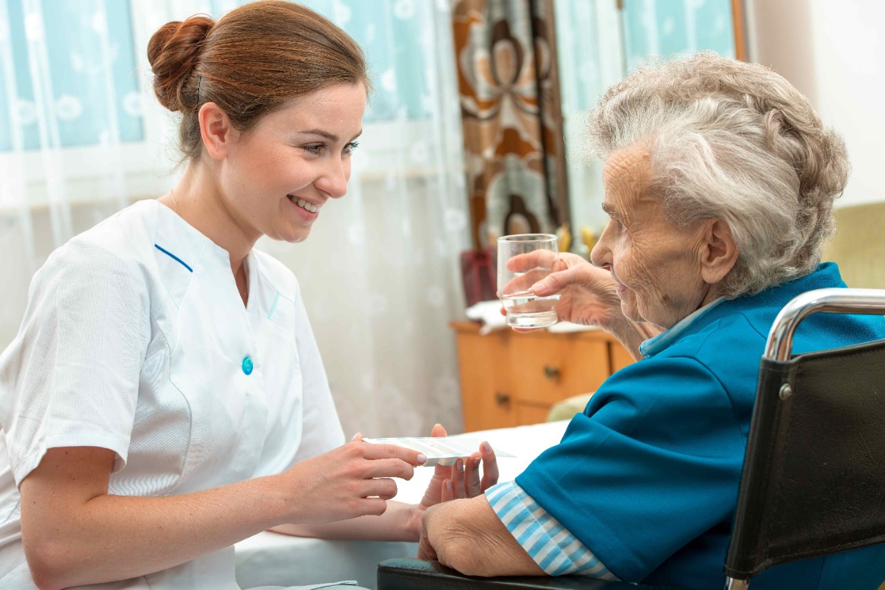 Krankenschwester gibt in Pflegeeinrichtung Medikamente an Rentnerin Krankenschwester gibt in Pflegeeinrichtung Medikamente an Rentnerin